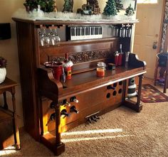 an old fashioned piano with christmas decorations on it's top and bottom shelf, in a living room