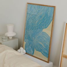 a painting is hanging on the wall next to a bed and nightstand with two vases