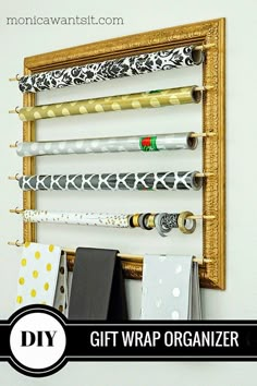 a diy gift wrap organizer hanging on a wall with gold frame and black polka dots