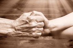 two people holding hands over a wooden table