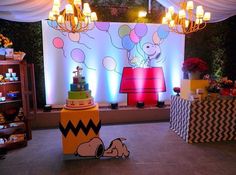 a birthday cake sitting on top of a table in front of a wall with balloons