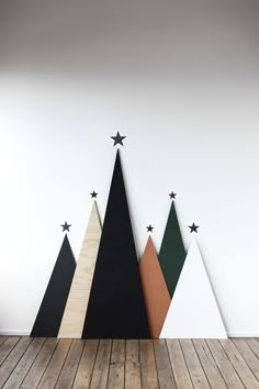 three wooden christmas trees with black, white and green ones in the middle on a wood floor