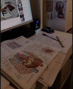 an open book sitting on top of a desk next to a computer monitor