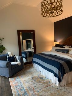 a bedroom with a bed, chair and mirror on the wall next to an area rug