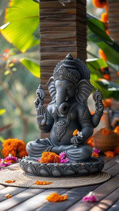 an elephant statue sitting on top of a wooden table next to flowers and leaves in the background