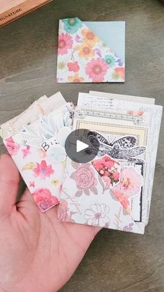 a person is holding several small cards in their hand and the other one has flowers on it