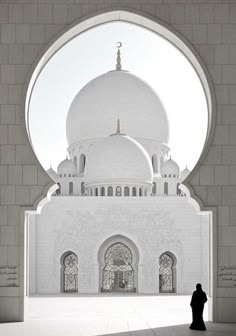 a person standing in front of a large white building with arches and domes on it