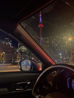 the view from inside a car at night with city lights in the distance and buildings lit up