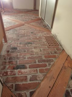 an image of a brick floor with grate in the middle and door on the other side