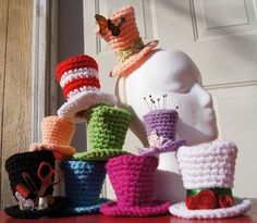 several crocheted hats sitting on top of a table next to a white mannequin