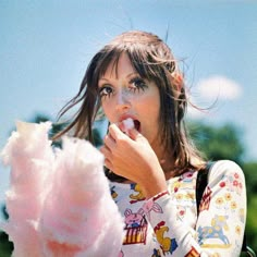 a woman eating cotton floss outside on a sunny day