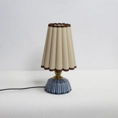 a lamp that is sitting on top of a white surface with a cord attached to it