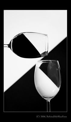 two wine glasses sitting next to each other in front of a black and white background