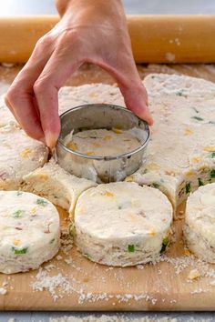 a person is spreading cheese on top of some bread rolls with a cookie tin in front of them