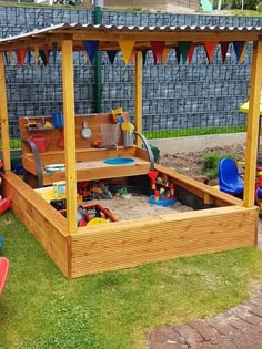 a child's sandbox in the middle of a yard with toys all around