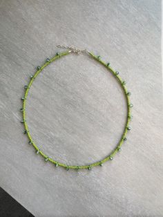 a green beaded necklace on a white surface