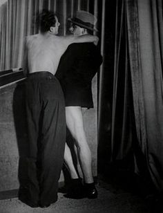 two men standing next to each other in front of curtains