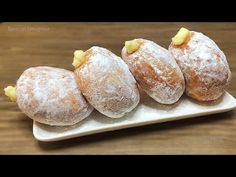 four powdered doughnuts on a white plate with pineapple chunks in the middle