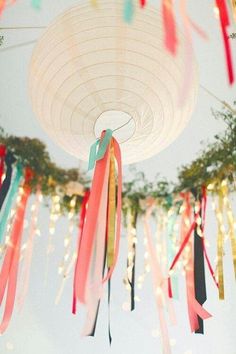 colorful streamers hang from the ceiling in front of a blue sky and tree with lights