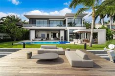 an outdoor living area with couches and tables next to a swimming pool in front of a large house