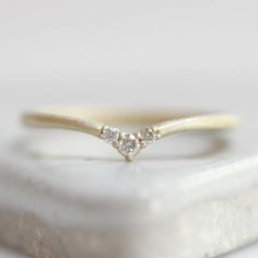 a three stone diamond ring sitting on top of a rock