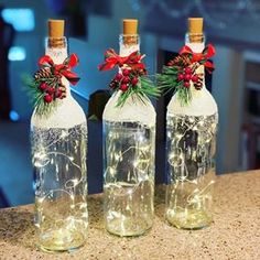 three wine bottles with lights in them sitting on a counter