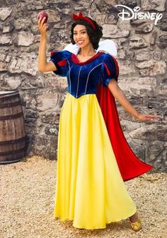 a woman dressed as snow white holding an apple in front of a stone wall with the words disney written on it