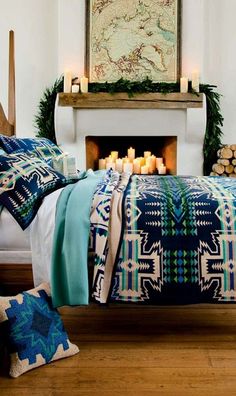 a bed room with a neatly made bed next to a fire place and candles on the table