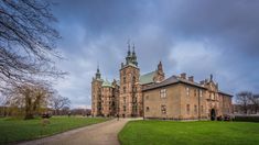 an old building with two towers and a walkway leading up to the front door on a cloudy day