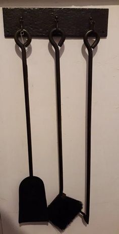 three black brooms hanging from hooks on a wall