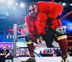 a man in red fur coat standing on top of a wrestling ring