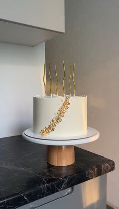 a white cake with gold sprinkles sitting on top of a counter