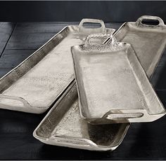 two silver trays sitting on top of a wooden table