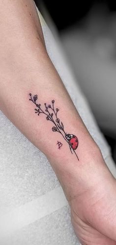 a ladybug tattoo on the left inner arm and wrist is shown in black ink