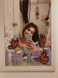 a woman is taking a selfie in front of a mirror with butterflies on it