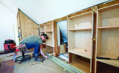 a man working on shelves in a room with unfinished walls and flooring being installed