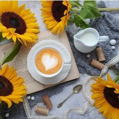 there is a cup of coffee on the table with sunflowers and other items