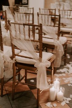 the chairs are decorated with white ribbons and candles