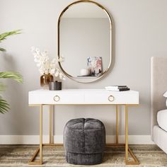 a black and gold console table with a round mirror above it, next to a white couch