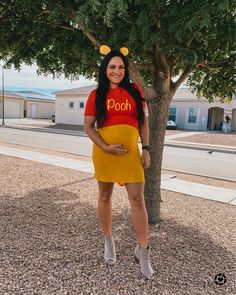 a woman in winnie the pooh costume standing next to a tree with her hands on her hips