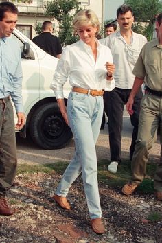 the woman is walking down the street with her hand in her pocket and two men standing behind her