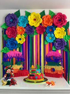 a table topped with a cake covered in colorful paper flowers and decorations on top of it