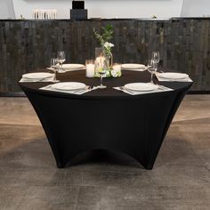 a black table with white plates and silverware on it in front of a wall