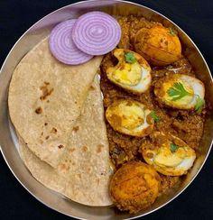 a metal plate topped with eggs and tortillas next to an onion on top