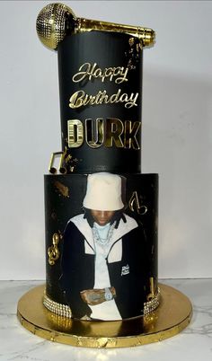 a black and gold birthday cake with the image of a rapper on it's side