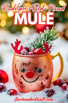 a red nose reindeer mug sitting on top of snow covered ground with christmas decorations around it