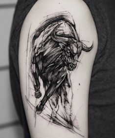 a black and white photo of a bull tattoo on the left upper half of the arm