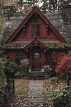 a red house in the fall with leaves on the ground