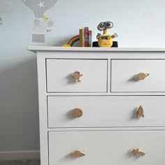 a white dresser with gold knobs in a child's room