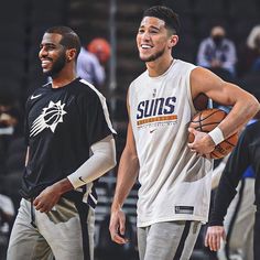 two men standing next to each other on a basketball court